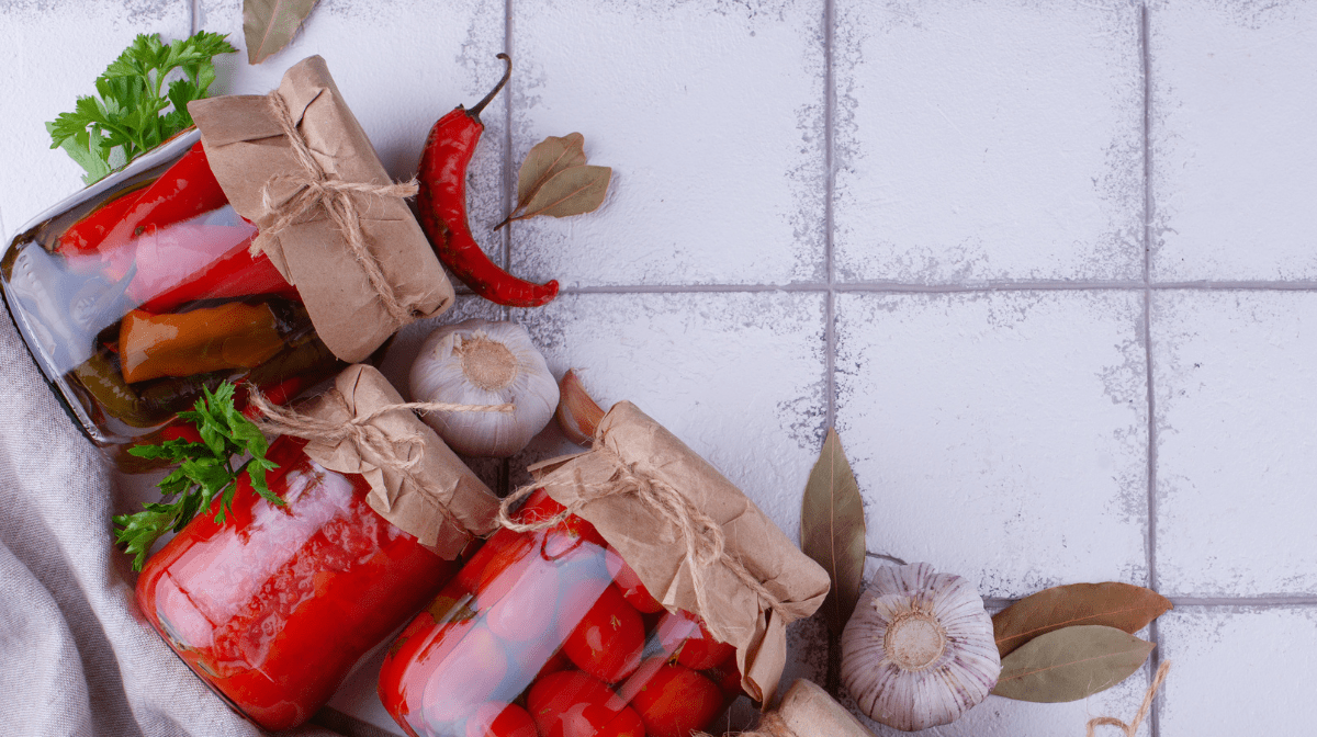 Fermented peppers and vegetables in jars on a white tiled surface