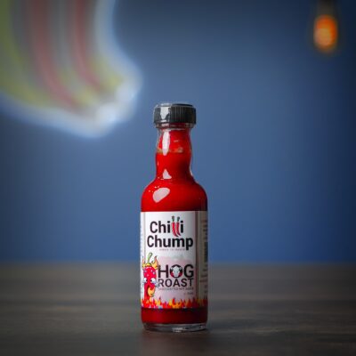 ChilliChump Hog Roast handcrafted hot sauce in a 50ml bottle, bright red sauce with a black cap, against a blue background.